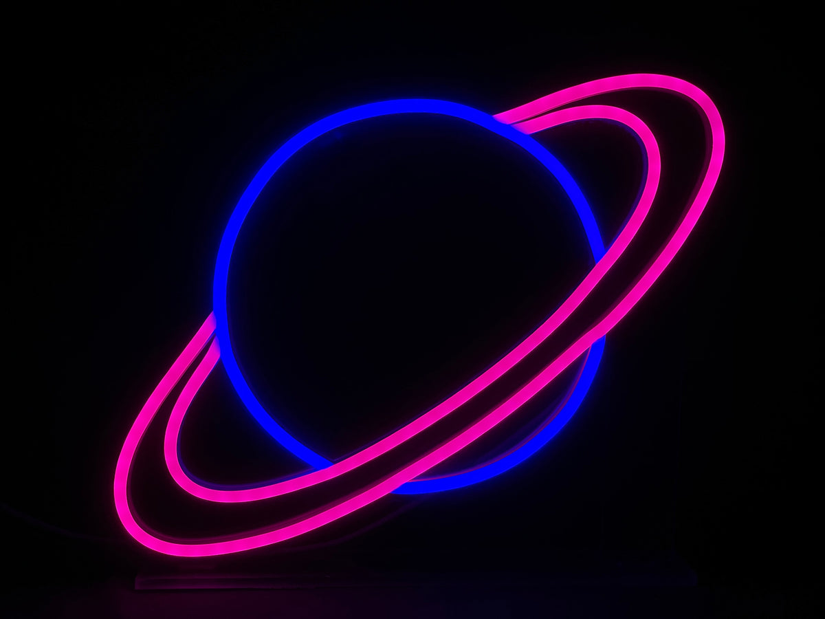 Close-up photograph of the 'Universe' desk neon sign glowing brightly in a dark environment, showing detailed colors.
