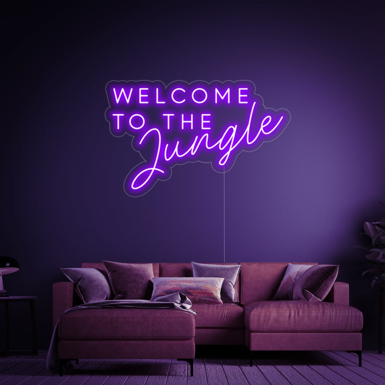 A illuminated 'Welcome to the Jungle' neon sign in bright green, hanging in a stylish lounge area with comfortable modern furniture.