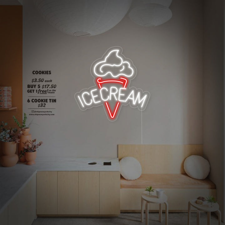 A illuminated 'Ice Cream' neon sign is mounted on a clear backboard against a cafe wall, with a menu board featuring blurred text visible in the background.