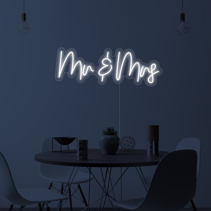 A photorealistic depiction of the 'Mr and Mrs' neon sign mounted on a clean acrylic backboard, glowing in a tastefully designed dining room setting.